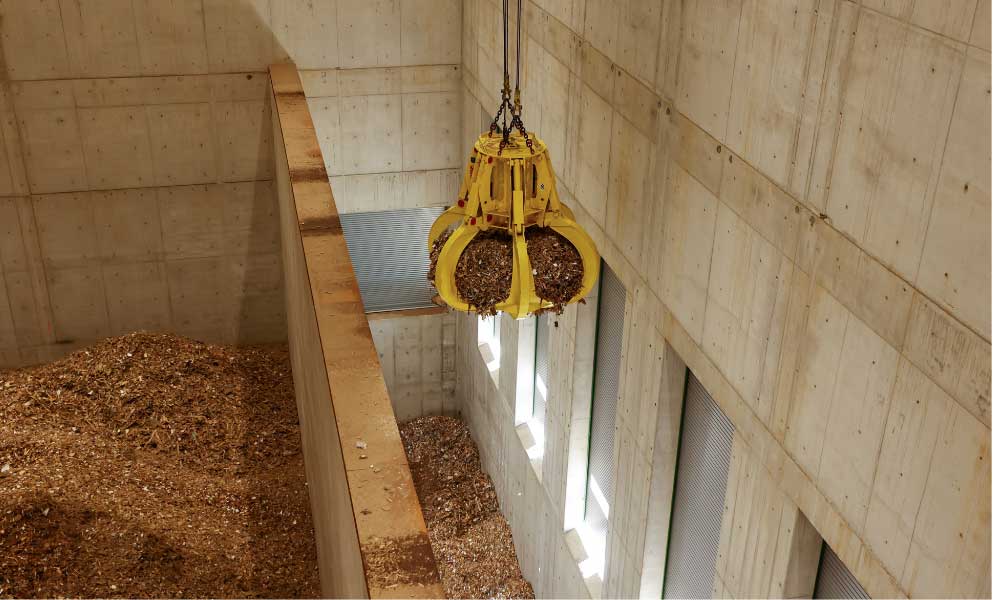 Greifer holt sich eine Menge Holzschnitzel zum Weitertransport