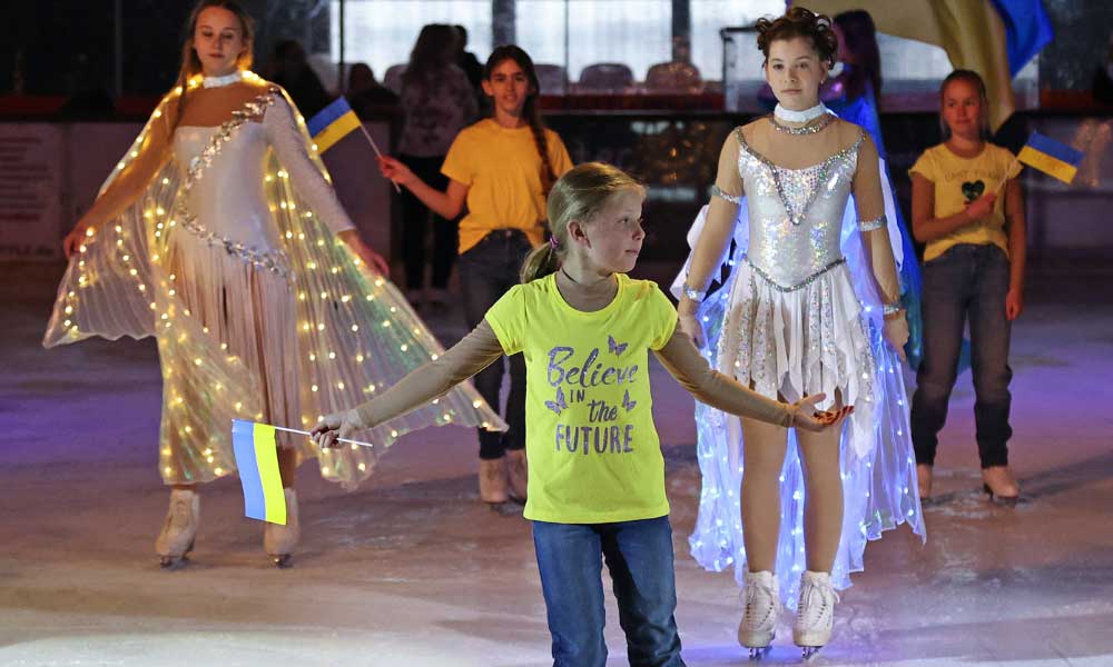 Eistänzerinnen mit Kostüm und Ukkraineflagge beim Lauf des friedens beim Energy on Ice