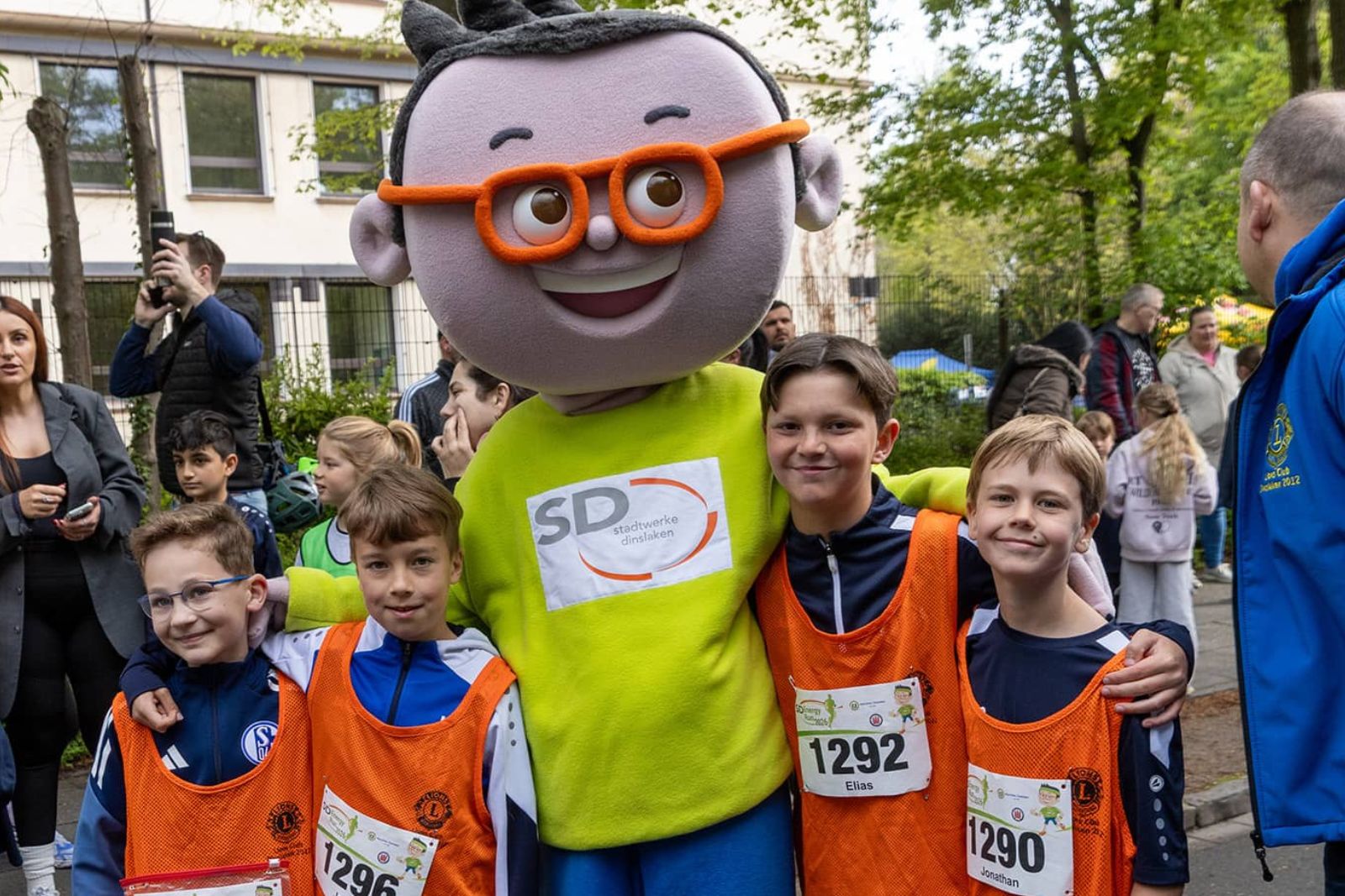 DIN-Maskottchen posiert mit vier Kindern