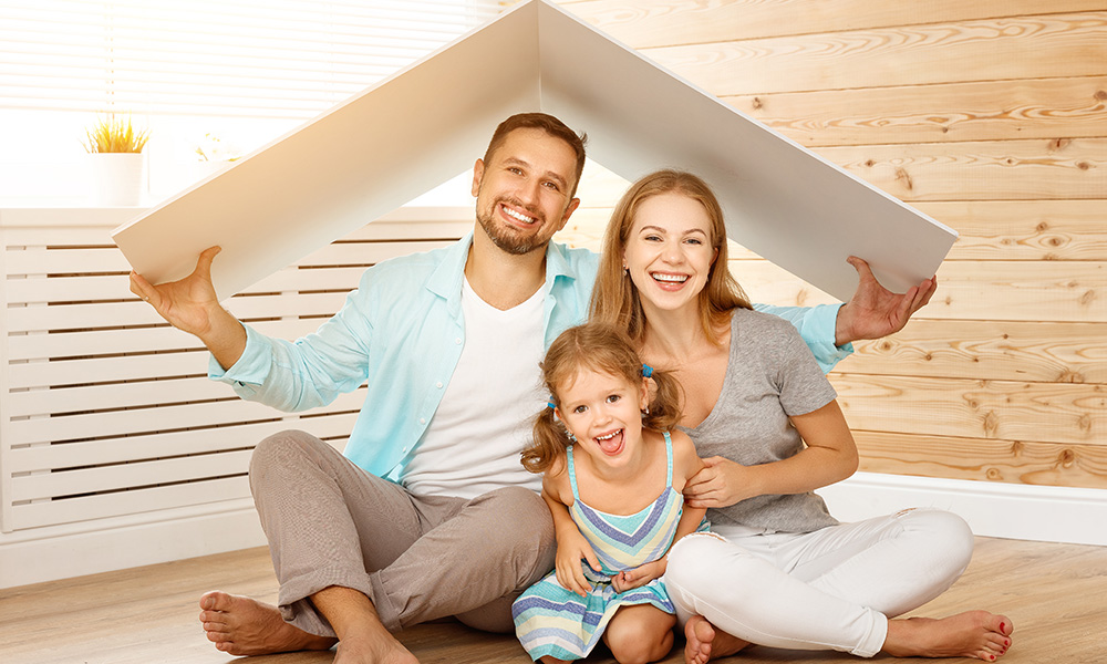 Junge Familie mit Mutter, Vater und Kind im neuen Zuhause unter einem stilisierten Dach – Symbolbild für Wohnen und Familie.