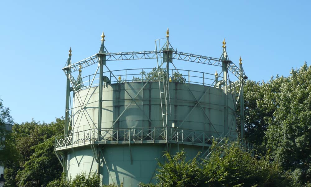 Der Gasometer der Stadtwerke Dinslaken ist von Bäumen umgeben. Seine Zinnen glänzen im Sonnenlicht.
