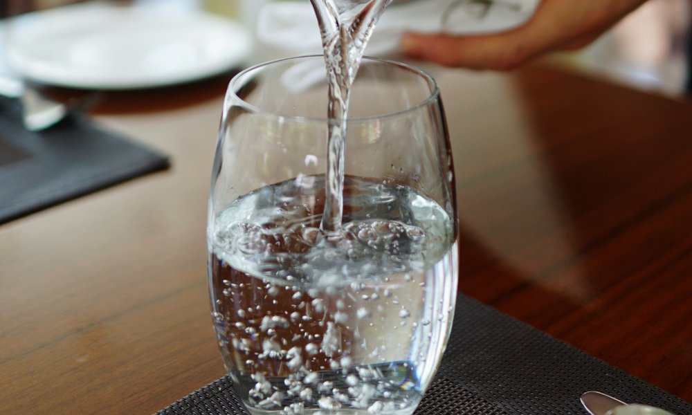 Trinkwasser wird sprudelnd in ein Wasserglas gefüllt.