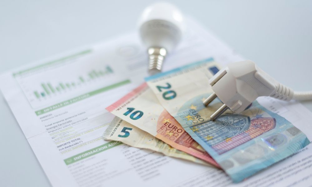 Stecker und LED-Leuchte liegen liegt auf Geldscheinen und einer Rechnung