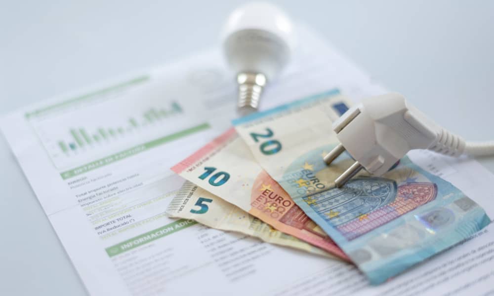 Geldscheine und eine Glühbirne liegen auf einer Stromrechnung
