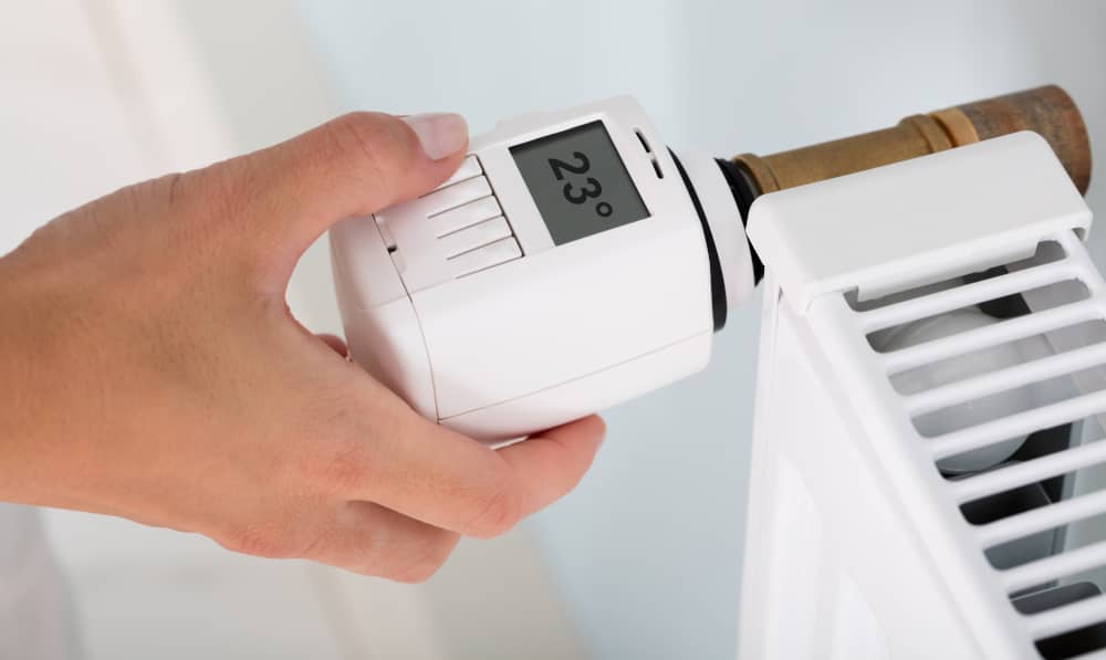 Eine Hand am Thermostat einer Heizung