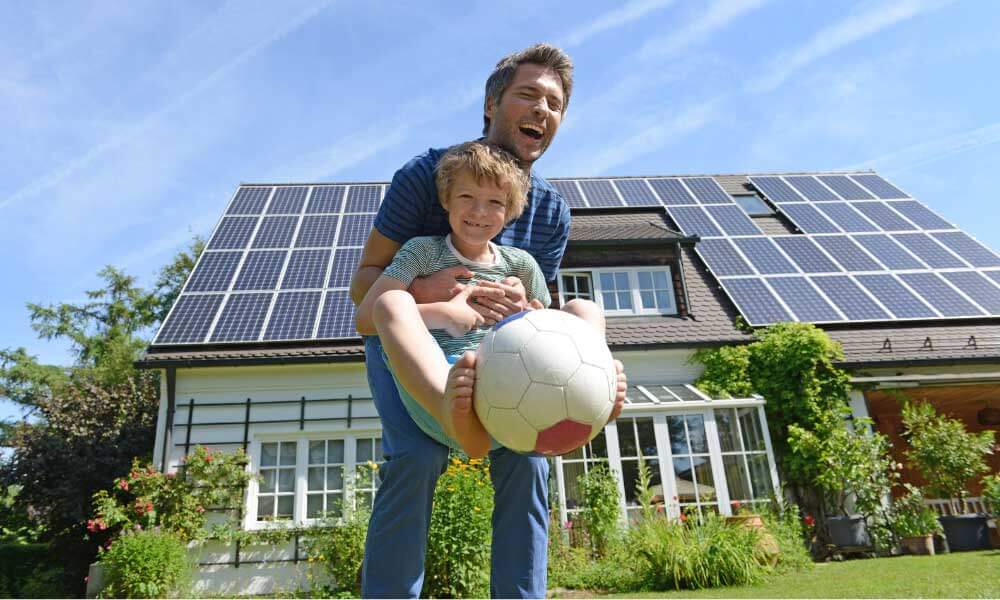 Mann mit Sohn vor Haus mit Solaranlage