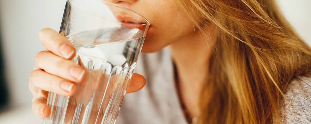 Eine Frau trinkt ein Glas Wasser.
